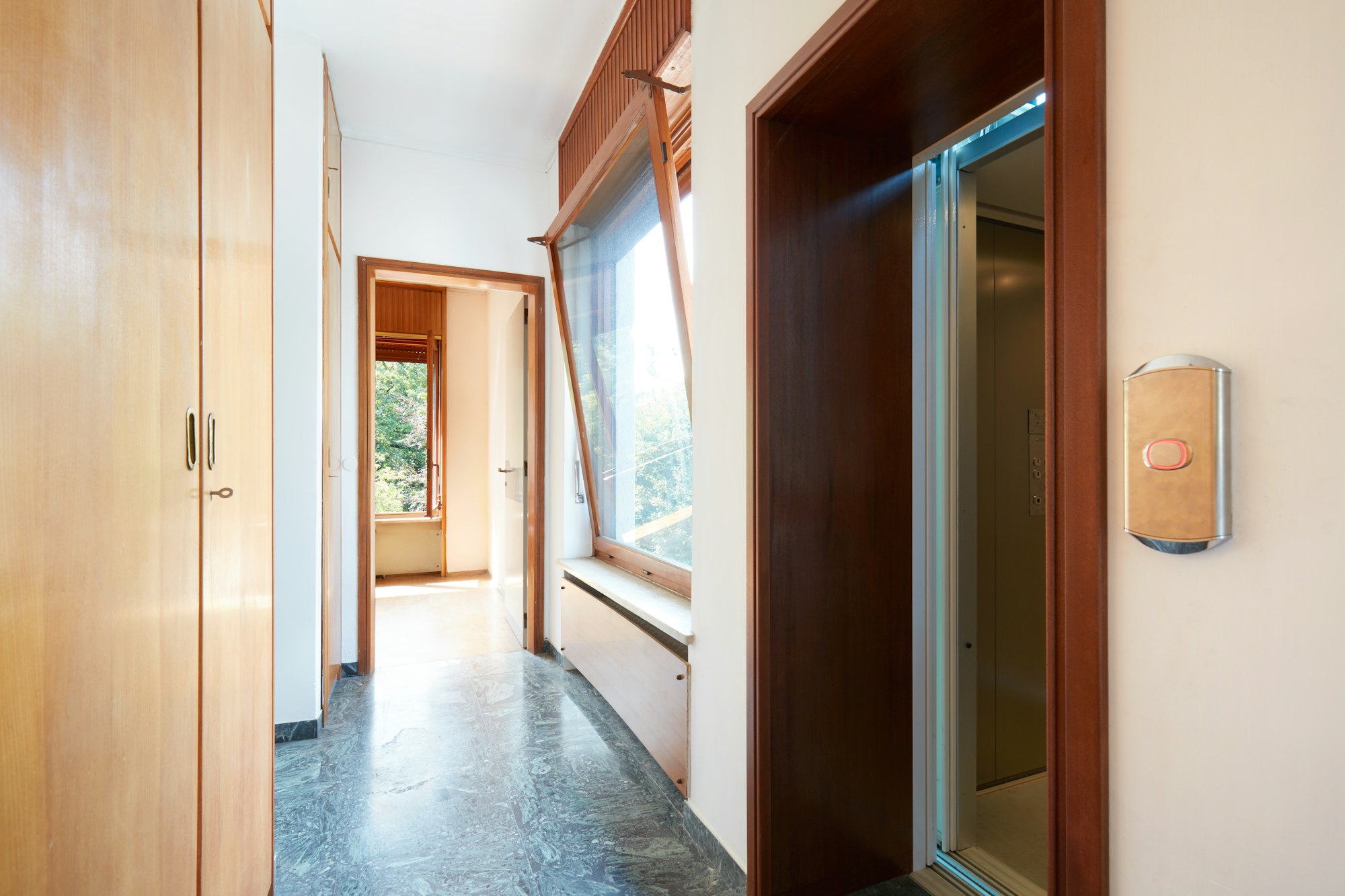 Corridor with wooden wardrobe, window and elevator door